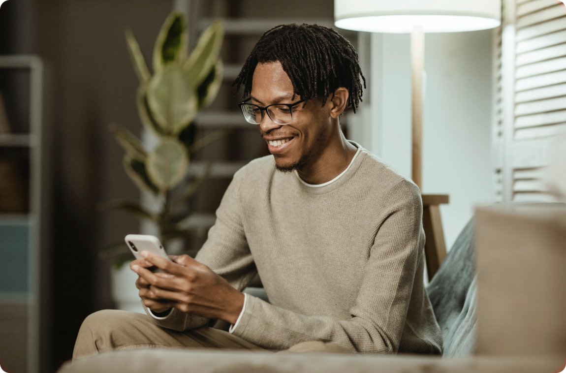 Homem negro de camiseta bege no celular